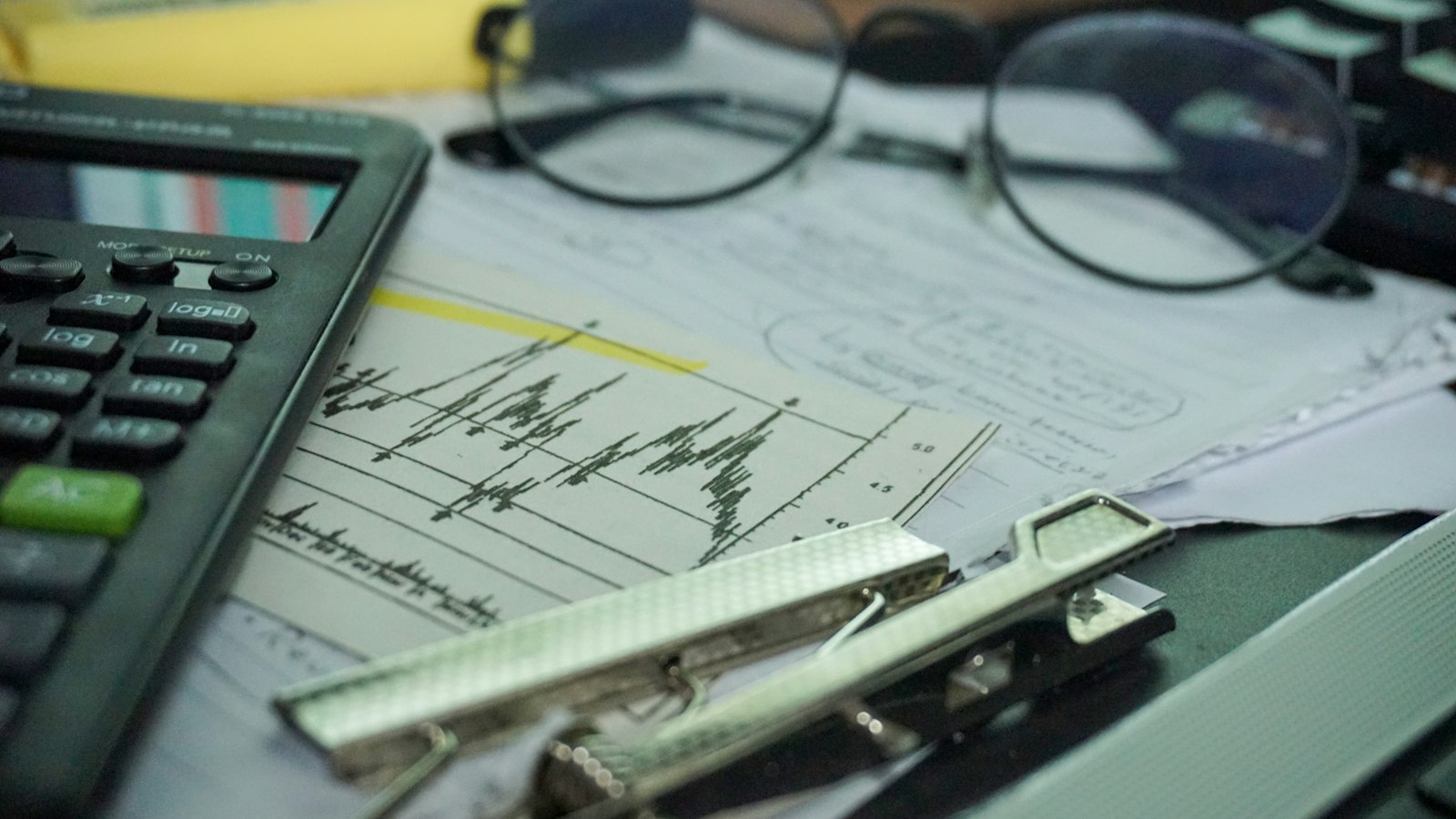 Calculator, papers and glasses on a desk